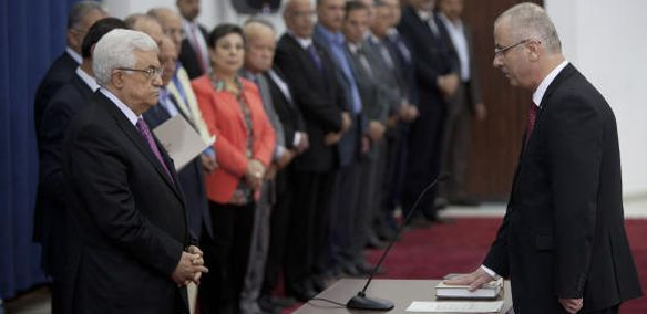 Palestinian Prime Minister Rami Hamdallah, right, puts his hand on the Quran in front of Palestinian President Mahmoud Abbas during a swearing-in ceremony of the unity government in the West Bank city of Ramallah on Monday, June 2, 2014. (AP Photo/Majdi Mohammed) (AP Photo/Majdi Mohammed)
