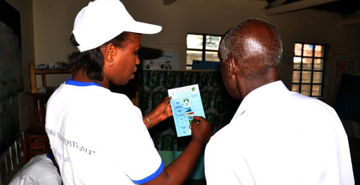A returning officer guides an elderly man at a polling station in Kiyovu in a past election. (File) A returning officer guides an elderly at a polling station-Kiyovu. (File)
