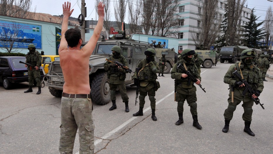 An unidentified man wearing military fatigues gestures in front of armed individuals blocking the center of Balaklava, near Sevastopol, on Saturday, March 1, 2014.(FP PHOTO/ VIKTOR DRACHEV) (FP PHOTO/ VIKTOR DRACHEV)