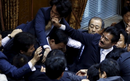 Lawmakers crowd around Yoshitada Konoike, chairman on the upper house special committee on security, as Masahisa Sato, right, of Japan’s ruling Liberal Democratic Party’s fist lands on opposition Democratic Party of Japan lawmaker Hiroyuki Konishi, top, during a vote at an upper house special committee session on security-related legislation at the parliament in Tokyo on Sept. 17, 2015 [photo credit: Yuya Shino/ Reuters] 