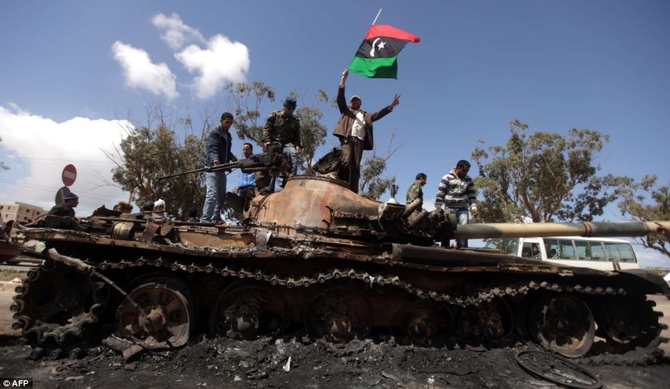 Libyan rebels wave their flag on top of the charred remains of a wrecked tank belonging to Moammar Gadhafi's forces at the western entrance to Benghazi, Libya. (photo credit: AFP) Libyan rebels wave their flag on top of the charred remains of a wrecked tank belonging to Moammar Gadhafi's forces at the western entrance to Benghazi, Libya. (photo credit: AFP)