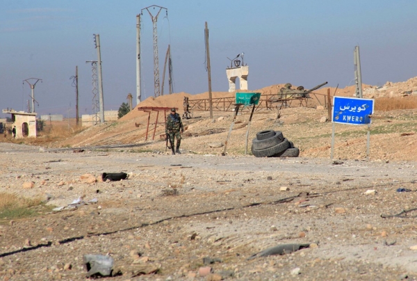 A Syrian pro-government fighter walks near the Kweyris military air base in the northern Syrian province of Aleppo on Nov. 11. Syria’s army broke a more than year-long jihadist siege of a military air base in the country’s north, scoring its first major breakthrough since Russia’s air campaign began. (photo credit: AFP/Getty Images)