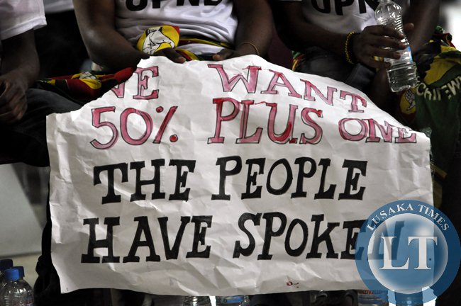 A woman from the UPND displays a placard demanding for the inclusion of the 50 plus one percent clause in the draft Zambian constitution (photo credit: Lusaka Times) A woman from the UPND displays a placard demanding for the inclusion of the 50 plus one percent clause in the draft Zambian constitution (photo credit: Lusaka Times)